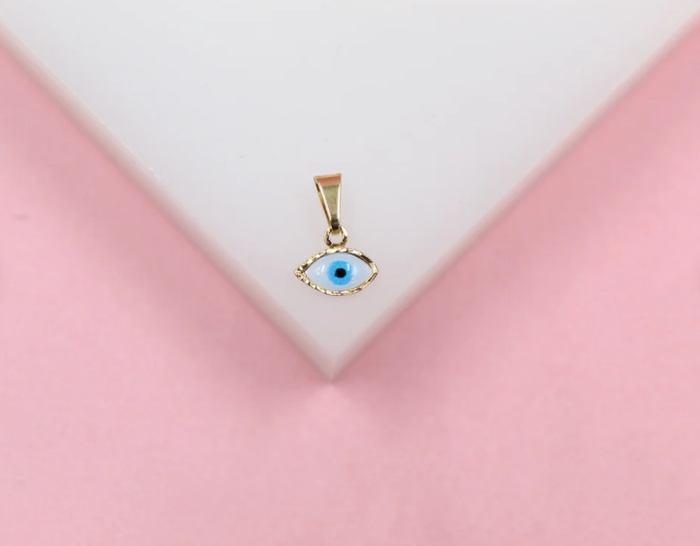 A gold evil eye pendant charm featuring white and blue enamel rests against a white and pink display.