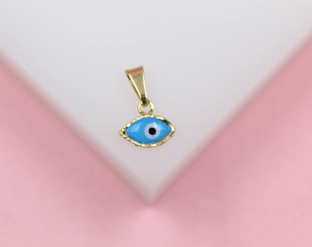 A gold evil eye pendant featuring blue and white enamel rests against a soft pink backdrop.