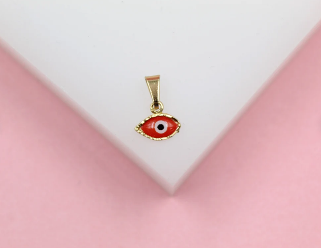 A gold evil eye pendant rests on a white display surface against a pink background.