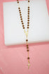 A catholic rosary necklace featuring smooth brown wooden beads and a delicate gold-plated crucifix rests on a white display surface.