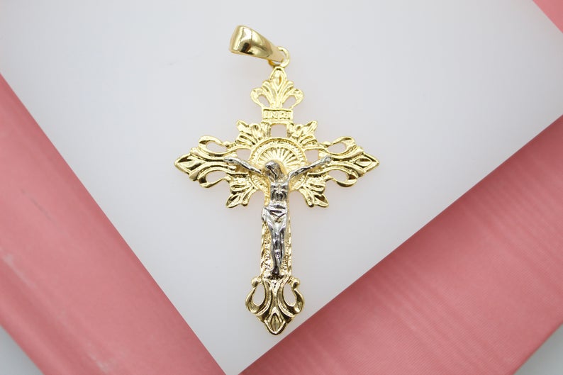 An intricate gold crucifix pendant features a white gold corpus on an ornate, filigree cross.