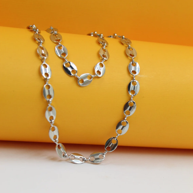 A shiny silver coffee bean chain necklace drapes elegantly over a vibrant yellow cylinder.