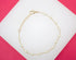 A delicate gold chain bracelet features alternating pearls and rests against a white and bright pink background.