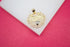 A gold heart-shaped pendant featuring the word "Mom" sits on a white surface against a vibrant pink background.