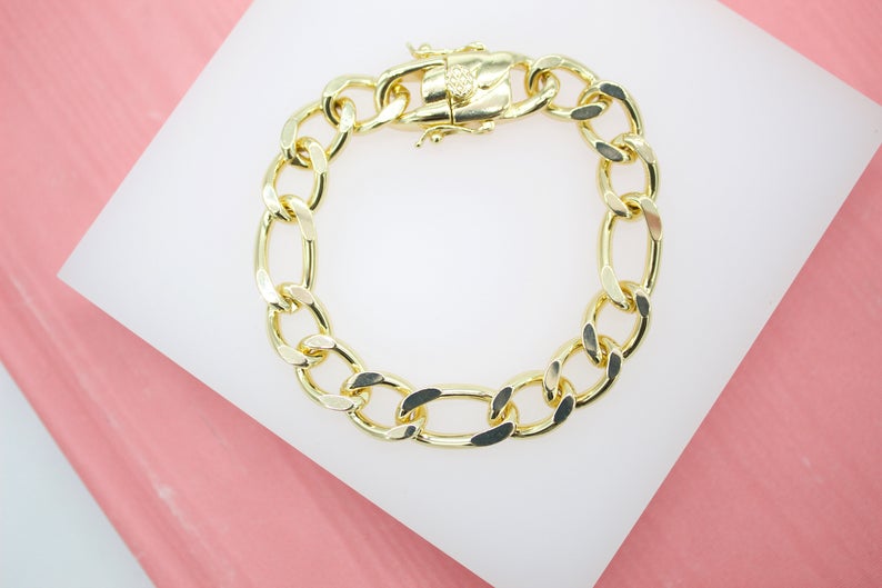 A thick gold chain bracelet rests on a white display stand against a pink background.