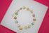 A gold butterfly charm bracelet displays colorful enamel butterflies in vibrant shades of red, blue, green, and yellow against a white display block.