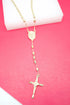 A shiny gold rosary necklace featuring oval beads and a crucifix rests against a vibrant pink and white background.