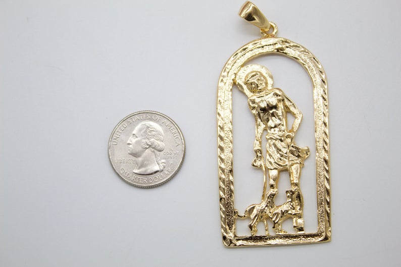 A gold San Martin de Porres pendant rests next to a US quarter coin to show its size.