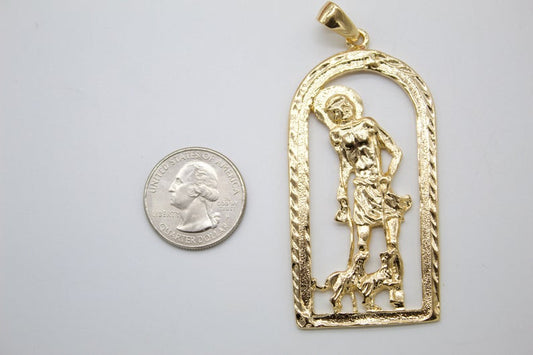 A gold San Martin de Porres pendant rests next to a US quarter coin to show its size.