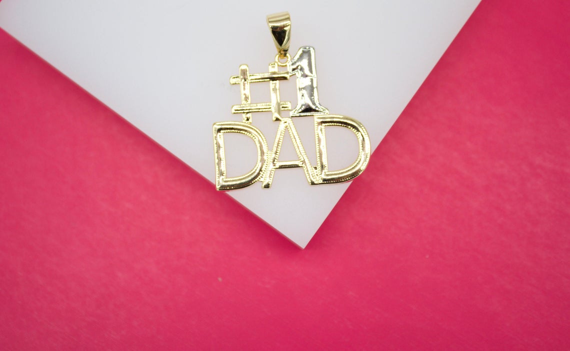 A gold "Number 1 Dad" pendant rests on a white and pink background.