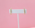 A pair of gold beaded climber earrings rests on a white display card against a soft pink background.