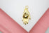 A polished gold hand charm rests on a white and pink background, showcasing its detailed palm and dangling ring.