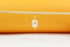A delicate freshwater pearl charm hangs from a thin gold hoop earring against a warm orange and white backdrop.
