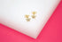 Two gold star-shaped stud earrings sparkle with pave diamonds against a white and pink background.