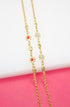 A delicate gold chain necklace features alternating red and white crystal flower stations against a bright pink and white background.