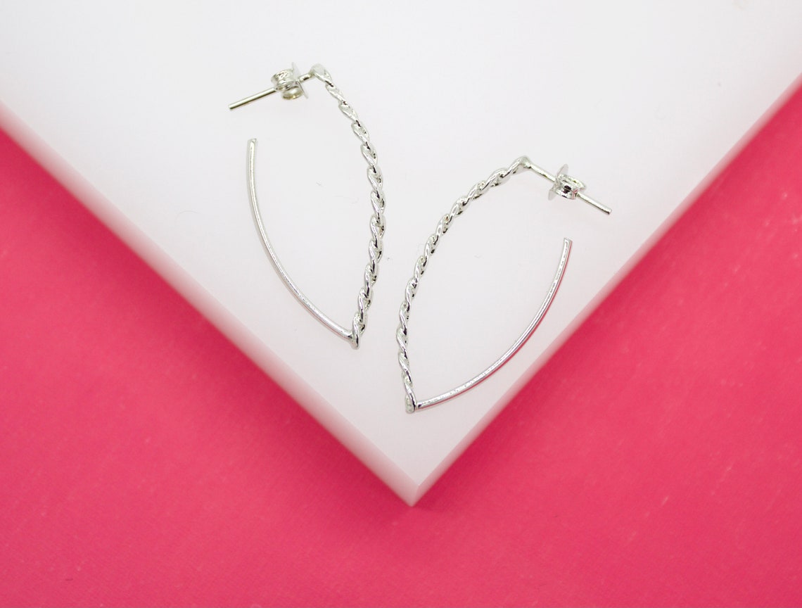 A pair of silver hoop earrings rests on a white and pink display surface.