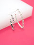 A pair of silver chain link hoop earrings rests on a pink and white background.