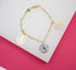A delicate gold link charm bracelet displays three cutout rose flower charms in yellow, white, and rose gold against a white and pink background.