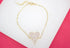 A gold chain bracelet features a sparkling, pave diamond-encrusted heart pendant centered on a white display surface.