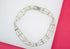 A multi-strand silver bracelet featuring sparkling rhinestones rests on a white and pink surface.
