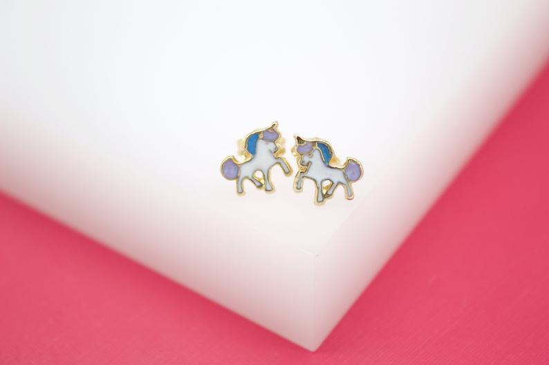 A pair of gold unicorn stud earrings features enamel details in blue, purple, and white.