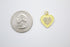 A shiny gold heart-shaped charm with yellow enamel and a pavé cubic zirconia center rests next to a US quarter coin for scale.