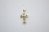 A delicate gold cross pendant features sparkling cubic zirconia stones set against a neutral background.