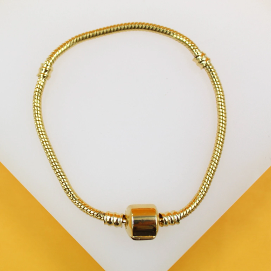 A gold-plated snake chain charm bracelet rests on a white and yellow surface.