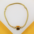 A gold-plated snake chain charm bracelet rests on a white and yellow surface.