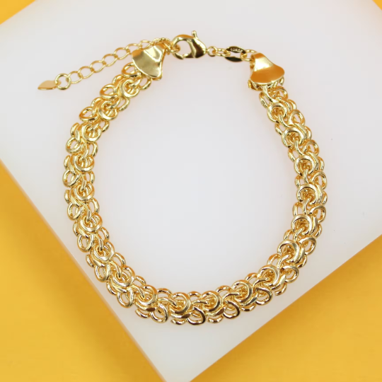 A gleaming 14k gold Byzantine link bracelet rests gracefully on a white display surface against a vibrant yellow background.