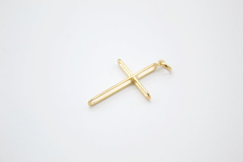 A sleek gold cross pendant rests on a clean white background.