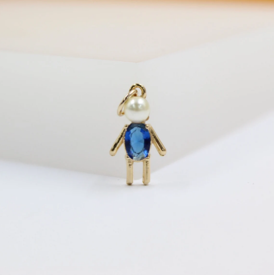 A gold pendant shaped like a little boy features a white pearl head and a vibrant blue crystal body.