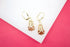 A pair of gold leverback earrings features intricate filigree cages cradling shimmering reddish-brown gemstones.