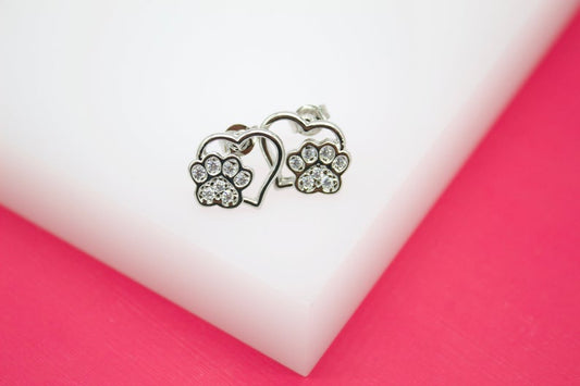 A pair of sterling silver heart and paw print stud earrings sparkle with embedded cubic zirconia stones.
