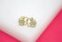 A pair of gold-plated paw print stud earrings featuring sparkling cubic zirconia stones nestled inside delicate heart frames rests on a white display surface.