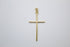 A polished gold cross pendant hangs against a plain white background.