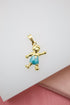A gold pendant shaped like a boy wearing blue enamel overalls gleams against a white and pink background.