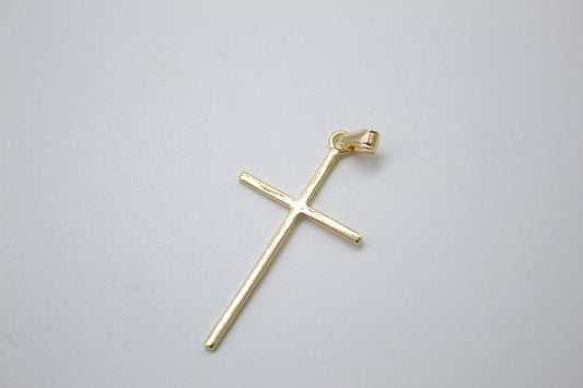A polished gold cross pendant rests on a neutral light gray background.