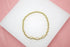 A gold bead stretch bracelet rests on a white display surface, featuring three sparkly pave-set rhinestone disco ball beads.