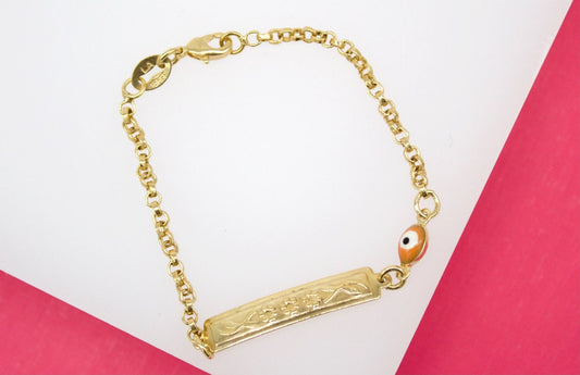 A gold chain bracelet features an engraved identification plate and a colorful enamel evil eye charm.