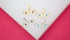 Four double-eyed evil eye charms rest on a white surface, featuring gold and silver finishes with white enamel and colorful red or blue centers.