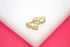 A pair of gold infinity-shaped hoop earrings encrusted with sparkling CZ stones rests on a white display surface.