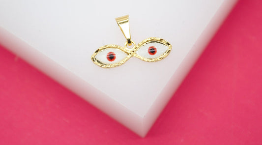 A gold evil eye pendant rests on a white display surface against a vibrant pink background.