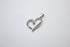 A sparkling diamond-encrusted silver heart pendant rests on a neutral background.