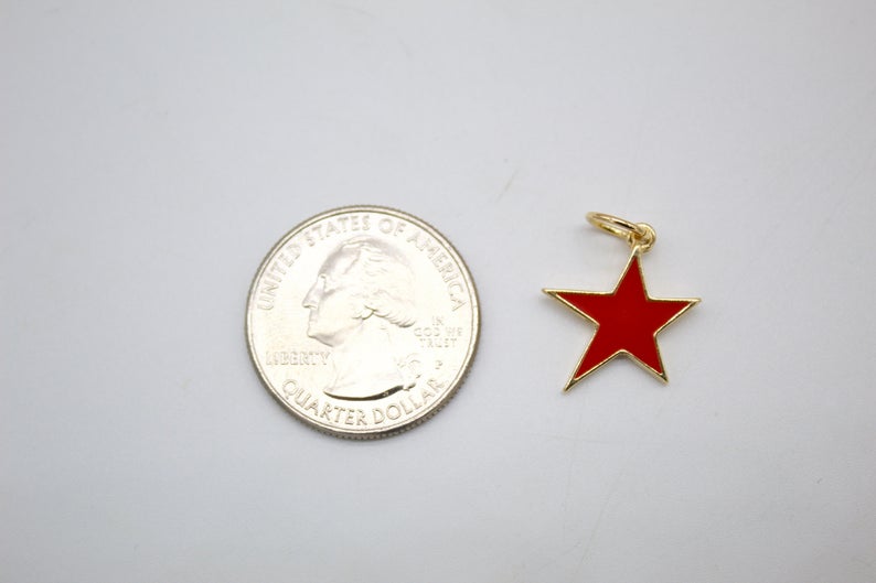 A small red and gold enamel star charm sits next to a US quarter coin for scale.