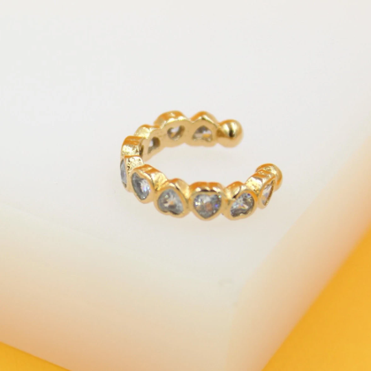 A gold-plated ear cuff features a continuous row of sparkling, heart-shaped zirconia stones.