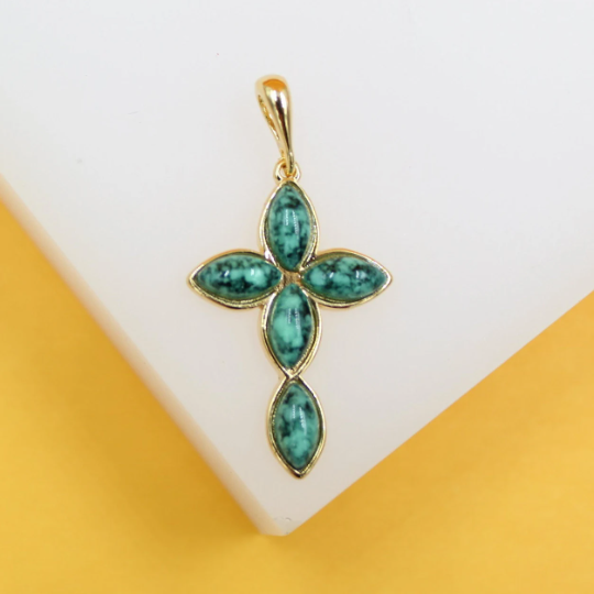 A gold-rimmed cross pendant features four polished turquoise gemstones arranged in a delicate marquise shape against a neutral background.