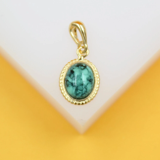 A gold pendant features an oval-shaped turquoise gemstone with intricate black veining, displayed against a neutral background.