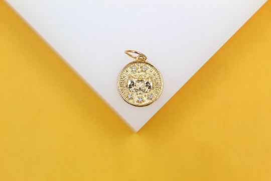 A detailed gold coin pendant rests on a white display against a vibrant yellow background.