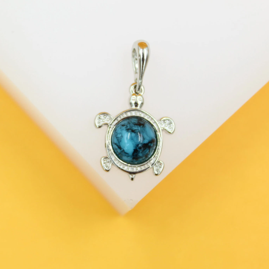 A silver turtle pendant featuring a mesmerizing blue marble shell rests against a geometric white and yellow background.